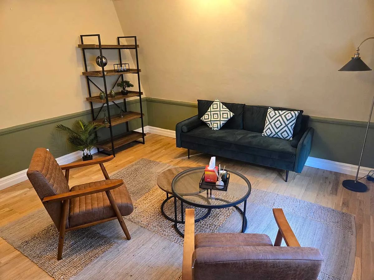 The therapy room at The Croydon Space: a warm room with a sofa, two armchairs and soft lamplight